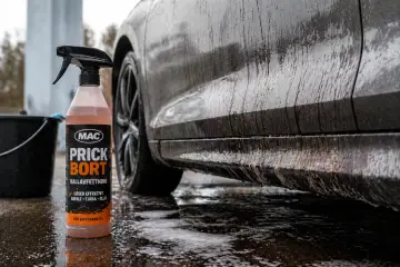 En flaska med MAC Prick Bort kallavfettning står bredvid en smutsig bil. Denna produkt är perfekt för att få bort asfalt, tjära och olja, vilket ger en renare bil.
