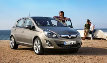Opel Corsa, idealne auto do 20 tys. na wakacyjny wypad nad morze. Para odpoczywa na plaży przy łodzi.