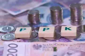 Pieniądze na stole, litery PPK i stosy monet. Zastanawiasz się, jak wypłacić pieniądze z PPK?