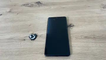 Czarny telefon i mały element głośnika na drewnianym tle.