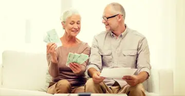 Uśmiechnięci seniorzy liczą pieniądze, być może planując wydatki z programu 500 plus dla seniora.