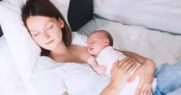 Matka śpi z dzieckiem przy piersi, doświadczając piękna laktacji.