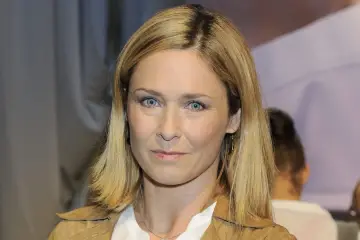 Beata z klanu, z niebieskimi oczami i blond włosami, patrzy wprost na widza.