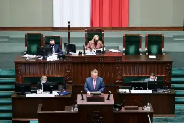 Posłowie w sejmie, dyskusja o tym, ile zarabia poseł. W tle polska flaga.