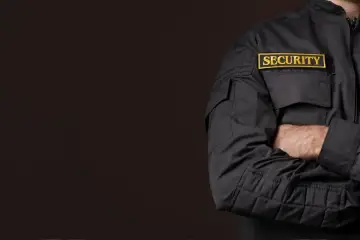 Pracownik ochrony w czarnej kurtce z naszywką "SECURITY". Zastanawiasz się, ile zarabia pracownik ochrony z bronią?