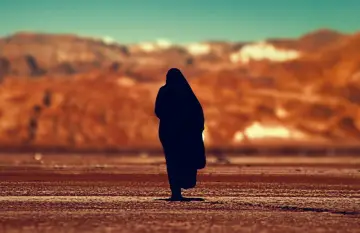 Eine Silhouette einer Person, die in der Wüste steht, erinnert an Johannes 1, wo das Wort am Anfang war.