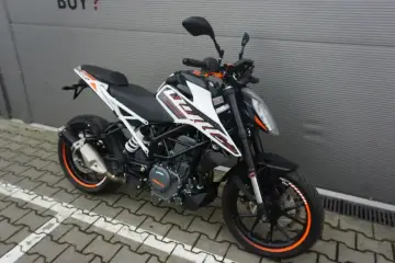 Czarny KTM Duke 390, zarejestrowany na 125, z pomarańczowymi akcentami na felgach i owiewkach, stoi na chodniku.