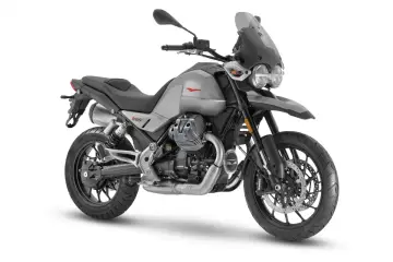 Srebrny motocykl Moto Guzzi V85 TT z czarnym siedzeniem i przyciemnianą szybą, gotowy na przygodę.