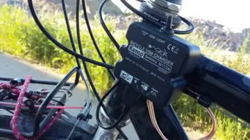 Ładowarka rowerowa Kemo zasilana przez **dynamo**, podłączona do kierownicy, z kablem USB.