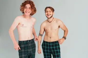Dwóch uśmiechniętych, znanych osób niebinarnych pozuje do zdjęcia.