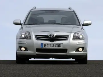 Srebrny kombi Toyota Avensis T25 z włączonymi światłami dziennymi i przeciwmgielnymi, gotowy do podróży.