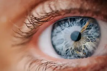 Makro zbliżenie niebieskiego oka z widocznymi wzorami siatkówki, przypominającymi zmiany w retinopatii barwnikowej.