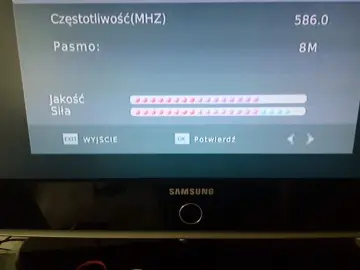 Ekran telewizora pokazuje jak sprawdzić siłę sygnału TV. Widoczne są wskaźniki jakości i siły sygnału, częstotliwość 586.0 MHz i pasmo 8M.