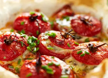 Pomodori ripieni al forno, dorati e succosi, con formaggio fuso e erba cipollina. Un'idea gustosa per un antipasto o un contorno.