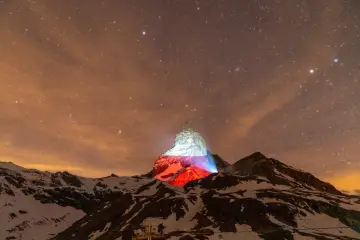 Górski szczyt, niczym polski Matterhorn, rozświetlony nocą polskimi barwami pod rozgwieżdżonym niebem.