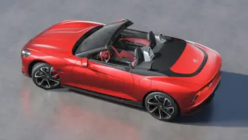 Czerwony MG Roadster z otwartym dachem, sportowe wnętrze, nowoczesne felgi i aerodynamiczne linie.