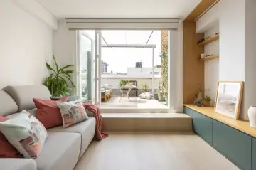 Ideas para decorar un salón rectangular: sofá gris, cojines coloridos, plantas y acceso a terraza.
