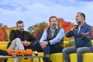 Trzech mężczyzn siedzi na kanapie. Jeden z nich, w niebieskiej koszuli, gestykuluje, opowiadając coś. Obok niego siedzi mężczyzna w kamizelce i okularach. Po drugiej stronie, w czarnej kurtce, siedzi trzeci mężczyzna. To ciekawy hrabi skład.