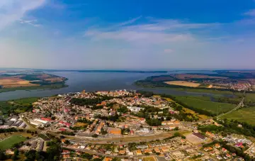 Widok z lotu ptaka na Kamień Pomorski. Miasto z czerwonymi dachami, port, jezioro i pola uprawne. Odkryj kamień pomorski atrakcje!