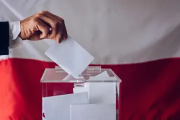 Dłoń wrzuca kartę do urny wyborczej. To ważny moment kampanii wyborczej, gdzie każdy głos ma znaczenie.