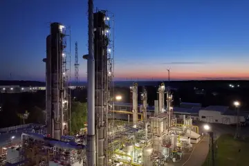 Wieczorna panorama kompleksu przemysłowego, symbolizującego postępującą industrializację. W oddali widać wiatraki.