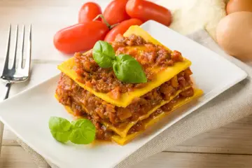 Pyszna, domowa lasagne z sosem bolońskim i listkami bazylii. Idealna porcja, by zaspokoić głód.