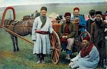 Grupa mężczyzn, prawdopodobnie tatarzy w Polsce, pozuje przy wozie konnym.