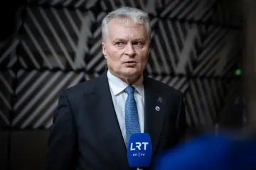 Prezydent Litwy w garniturze i krawacie udziela wywiadu przed mikrofonem LRT TV.