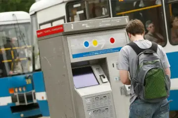 Chłopak z plecakiem kupuje mpk wrocław bilety ulgowe w automacie.