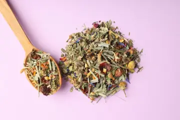 Mieszanka suszonych ziół i kwiatów na łyżce i obok. Dowiedz się, jak suszyć świeże zioła w piekarniku bez utraty koloru i aromatu.