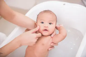Delikatna kąpiel niemowlaka w wanience. Czy można myć dziecko z gorączką? Tak, ale w letniej wodzie, by pomóc mu się ochłodzić.