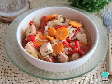 Pechuga de pollo en escabeche con zanahoria, pimiento rojo y cebolla, servida en un cuenco blanco sobre una base tejida.