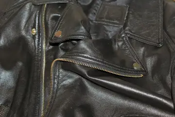 Dettaglio di una giacca in ecopelle nera con zip dorata e bottoni a pressione. Si pensa a come lavare giacca ecopelle in lavatrice.