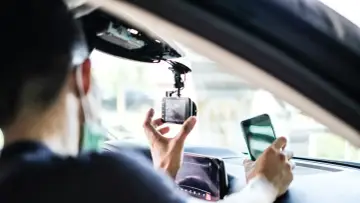 Mann installiert Dashcam im Auto, ADAC-Mitglieder profitieren von sicherer Fahrt.