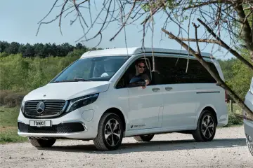 Vit eldriven husbil från Tonke parkerad på grusväg. En man med solglasögon sitter bakom ratten.
