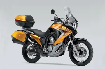 Złoty motocykl Honda Transalp 700 z kuframi. Dane techniczne tego modelu są imponujące.