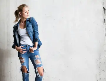 Stylowa blondynka w rozdartych jeansach i jeansowej koszuli. Inspiracja, jak nosić koszulę do jeansów.