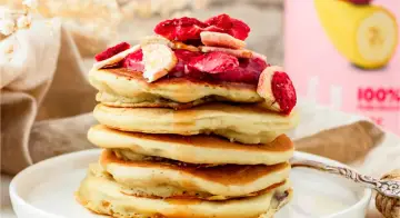 Stapel fluffiger Pfannkuchen mit gefriergetrockneten Erdbeeren und Bananen, perfekt für gesunde Snacks selber machen.