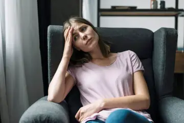 Zmartwiona kobieta w fotelu, zastanawia się, ile trwa odzyskanie dziecka z rodziny zastępczej.