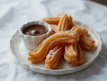 Churros co to? Złociste, chrupiące paluszki posypane cukrem, idealne do maczania w gorącej czekoladzie. Pyszna przekąska!