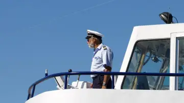 Kapitan na mostku statku, zastanawia się, ile zarabia marynarz.