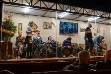 Na scenie siedzi kilka osób, w tym mężczyzna na wózku. W tle widać ekran z obrazem, jakby tkacz tworzył coś na nim.
