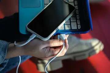 Dłoń podłącza kabel USB od telefonu do laptopa. Prosty sposób, jak połączyć telefon z laptopem, by przesłać dane lub naładować urządzenie.
