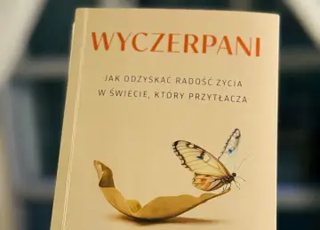 Okładka książki "Wyczerpani. Jak odzyskać radość życia w świecie, który przytłacza", z motylem na liściu.