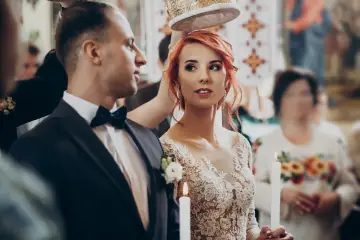Para ślubna w kościele, z koroną nad głowami. Panna młoda w koronkowej sukni, pan młody w garniturze. W tle goście. Zastanawiasz się, jakie dokumenty do ślubu?