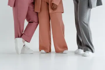 Trzy osoby w eleganckich stylizacjach. Jedna w różowych spodniach, druga w brzoskwiniowych, a trzecia w szarych. Zastanawiasz się, jaka marynarka do szarych spodni pasuje najlepiej?
