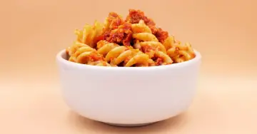 Miseczka pełna makaronu fusilli z aromatycznym sosem, w którym dominują nuty pesto i słodycz suszonych pomidorów.