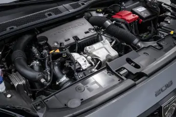 Silnik 1.2 PureTech z turbosprężarką w samochodzie Peugeot 208. Widoczne elementy układu dolotowego, akumulator i osłony.