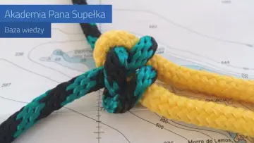 Węzeł baryłkowy, wykonany z żółtej i czarno-turkusowej liny, prezentuje się na tle mapy morskiej.