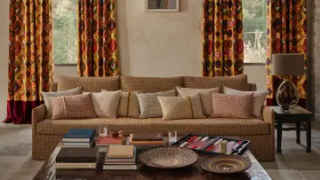 Cortinas con estampado geométrico vibrante, un sofá acogedor y cojines texturizados. Las ultimas tendencias cortinas salon se reflejan en este espacio.